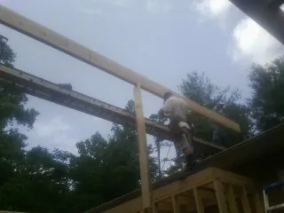 Carpenter setting a ridge beam over a new addition frame — Ice Dam Removal by Roofing Brothers in Saranac