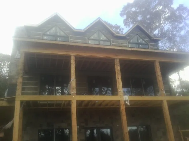 Dormers and porch framing on a large log home under construction — Roof Coating work by our crew in Saranac
