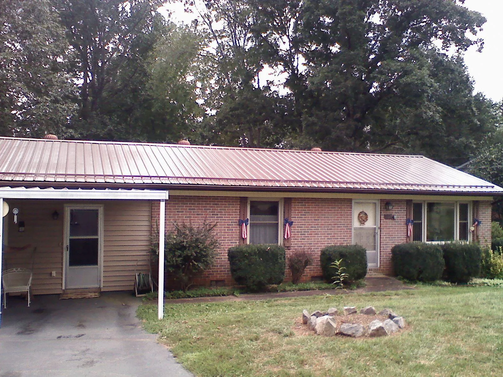 Bronze metal roof and carport on a brick ranch home — Roof Repair work by our crew in Saranac
